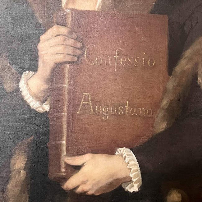 Philipp Melanchthon hält die Confessio Augustana fest.